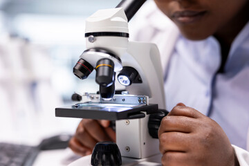 Close up of researcher focusing on a microscope with samples in chemistry lab. Using observation tool with tray for diagnostics, molecular analysis and discovery. Optics in bioscience.