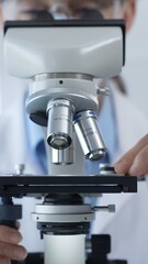 Female scientist wearing lab coat and protective glasses using a modern microscope in a laboratory setting, conducting research and experiments, close up. Health care, medicine and science concept