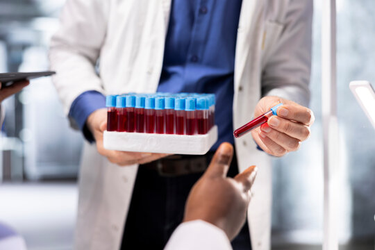 Close up of researching team performs experiment with blood samples in tray, using molecular biology and biochemistry. Colleagues contribute to medical discovery and nanotechnology advancements. - Powered by Adobe