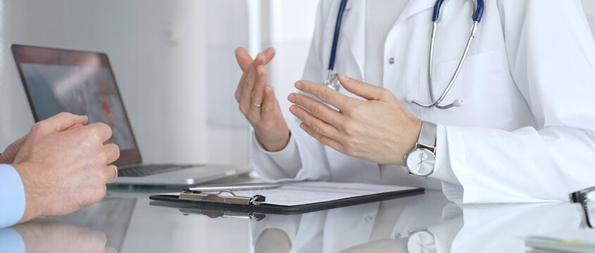 Doctor consulting patient, discussing medical information during a healthcare appointment at the clinic. Medicine, healthcare and science concept - Powered by Adobe