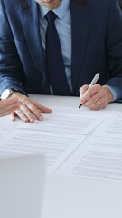 Obraz na płótnie Canvas Businessman signing a contract papers at the white desk in office, colleagues applauding to the successful results of negotiations. Business people concept