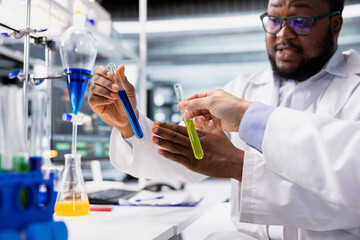 Close up of lab coworkers inspecting liquids in test tube, looking for breakthroughs during clinical trials. Team of specialists in research facility comparing chemicals vials, testing right formula