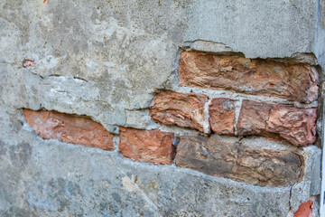 Damaged weathered stone grave wall showing exposed brick and crumbling mortar at old Powązki Cemetery Warsaw Poland. High quality photograph