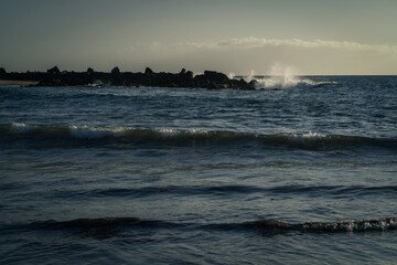 Waves breaking on the rocks on the beach in the evening.