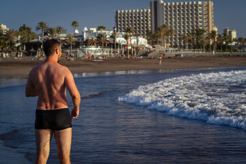 Athletic man running on the beach in the evening.