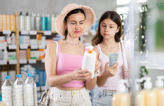Portrait of friendly family of mother and daughter customers holding, scan QR code on label and selecting cream or skin care product in modern drugstore - Powered by Adobe