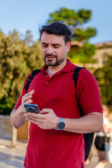 Fototapeta premium Man using smartphone while standing outdoors in a lively urban area during the evening