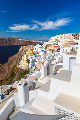 Vacation background. Vertical image of Oia village with famous white houses and blue churches on Santorini island, Aegean sea, Greece