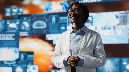 Joyous scientist reviewing medical scans projected on videowall. Happy researcher wearing lab coat standing in front of digital health dashboards backdrop, analyzing human anatomy, camera B
