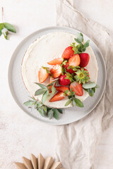 Beautifully decorated cake seen from above, featuring sweet fresh strawberries and elegant eucalyptus accents on a creamy white frosting