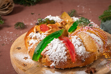 Colorful candied fruits and powdered sugar on a traditional Bolo Rei or Kings Cake, set on a wooden...