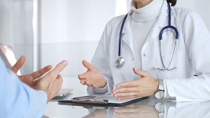 Doctor discussing medical information with patient during consultation, showing healthcare advice and diagnostic data on laptop. Medicine, healthcare and science concept