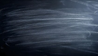 A close-up shot of a dark, dusty chalkboard with faint white chalk marks.