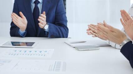 Professional business team clapping hands, celebrating successful presentation, showcasing collaborative spirit and corporate achievement in modern meeting space