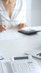 Close up of a calculator on financial documents, with an accountant taking notes, emphasizing accounting, finance, and tax preparation. Audit and taxes in business