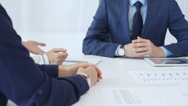 Business team engaging in a corporate meeting, discussing strategies while analyzing financial charts and graphs on a digital tablet alongside printed documents