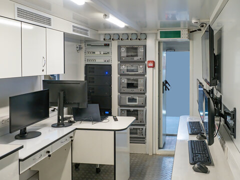 IT specialists operate computer monitors and server racks inside a mobile control room, managing data processing, system monitoring, and secure communication.