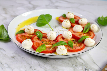 Caprese salad with tomatoes, mozzarella cheese and basil on a white plate