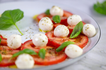 Caprese salad with tomatoes, mozzarella cheese and basil on a white plate