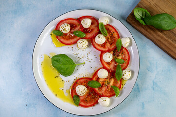 Caprese salad with tomatoes, mozzarella cheese and basil on a white plate