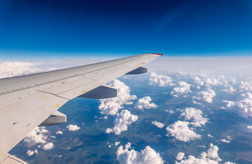 Obraz premium View from the airplane window at a beautiful cloudy sky and the airplane wing