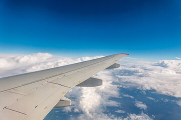 View from the airplane window at a beautiful cloudy sky and the airplane wing