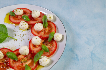 Caprese salad with tomatoes, mozzarella cheese and basil on a white plate