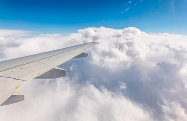 Fototapeta premium View from the airplane window at a beautiful cloudy sky and the airplane wing
