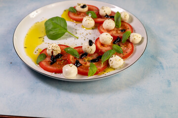 Caprese salad with tomatoes, mozzarella cheese and basil on a white plate