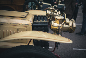 An antique car showcases its brass headlights, offering a glimpse into automotive history and design.