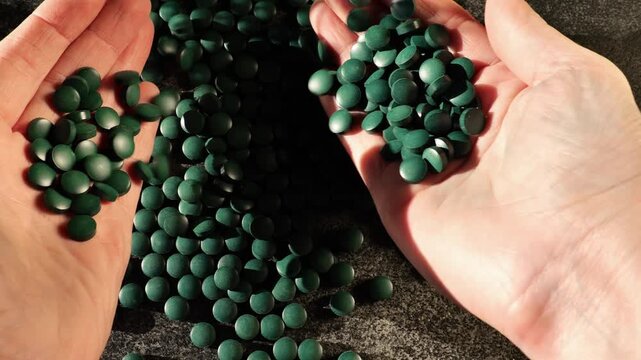 Green spirulina pills in hands. Algae in nutrition.Natural vegetarian source of protein. 4k footage
