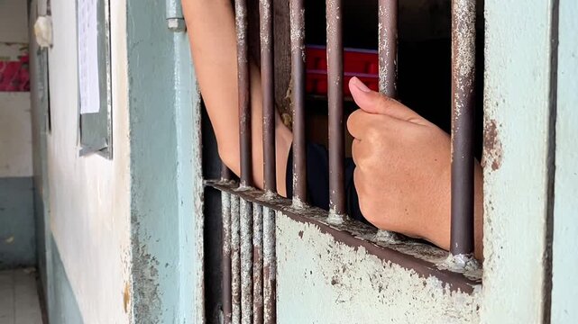 close up of prisoner hands in jail background.	