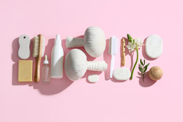 Different bath supplies for foot massage and flower on pink background