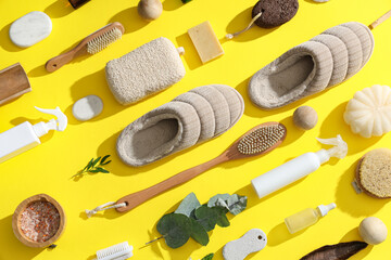 Different bath supplies for foot massage and slippers on yellow background