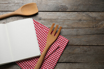Blank recipe notebook, napkin and wooden cutlery on wooden background