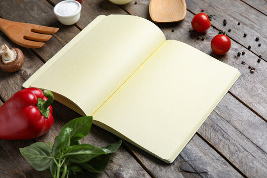 Composition with blank recipe notebook and ingredients on wooden background