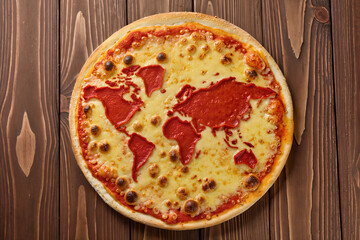 Creative pizza with a world map made of tomato sauce on melted cheese, placed on a wooden table. Concept of global cuisine and international food.