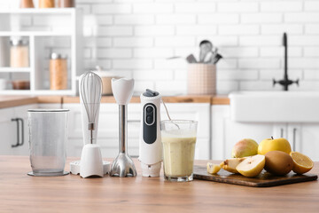 Modern blender with different attachments and fresh fruits on table in kitchen