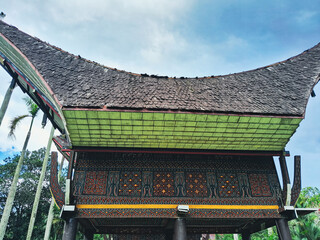 Traditional South Sulawesi house with high wooden stilts and curved roof, showing intricate...