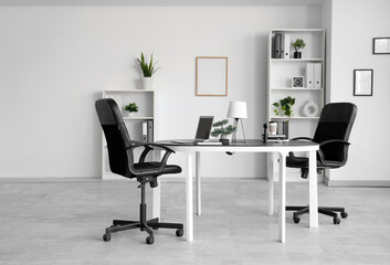 Interior of modern office with comfortable workplace near white wall