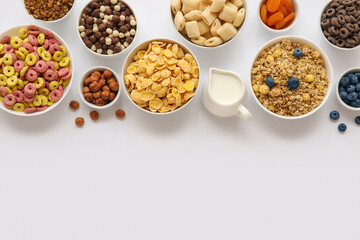 Bowls with different cereals and ingredients on white background