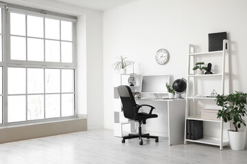 Modern workplace with computer and black swivel chair near white wall in office