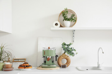 Modern coffee machine, sweet buns and vase with eucalyptus twigs on table in kitchen © Pixel-Shot