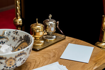 Golden and silver holy oil containers with ornate porcelain bowl and white envelope on wooden altar — traditional baptism or anointing ceremony items symbolizing faith, purity, and sacred blessing.
