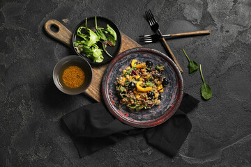 Plate with healthy quinoa salad and ingredients on black grunge background