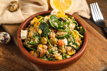 Healthy quinoa salad in bowl on wooden background, closeup