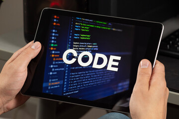 a male hands holding a tablet with the phrase code over a writing code concept