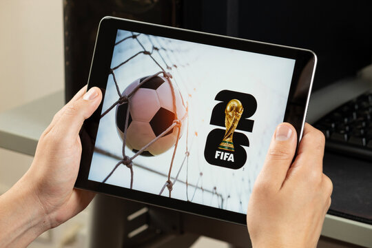a male hand holding an iPad with the fifa world cup 2026 logo at the right side corner with a goal concept