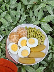 A plate of healthy breakfast. Balance diet. Boiled egg, steamed banana, boiled edamame, tangerine.