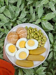 A plate of healthy breakfast. Balance diet. Boiled egg, steamed banana, boiled edamame, tangerine.